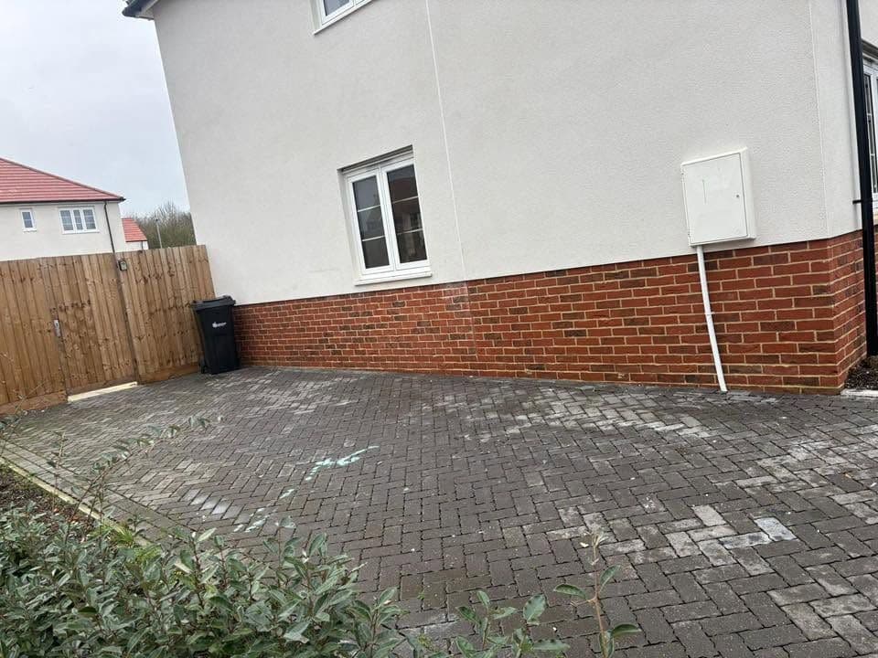 Clear block-paved driveway beside a rendered new-build house