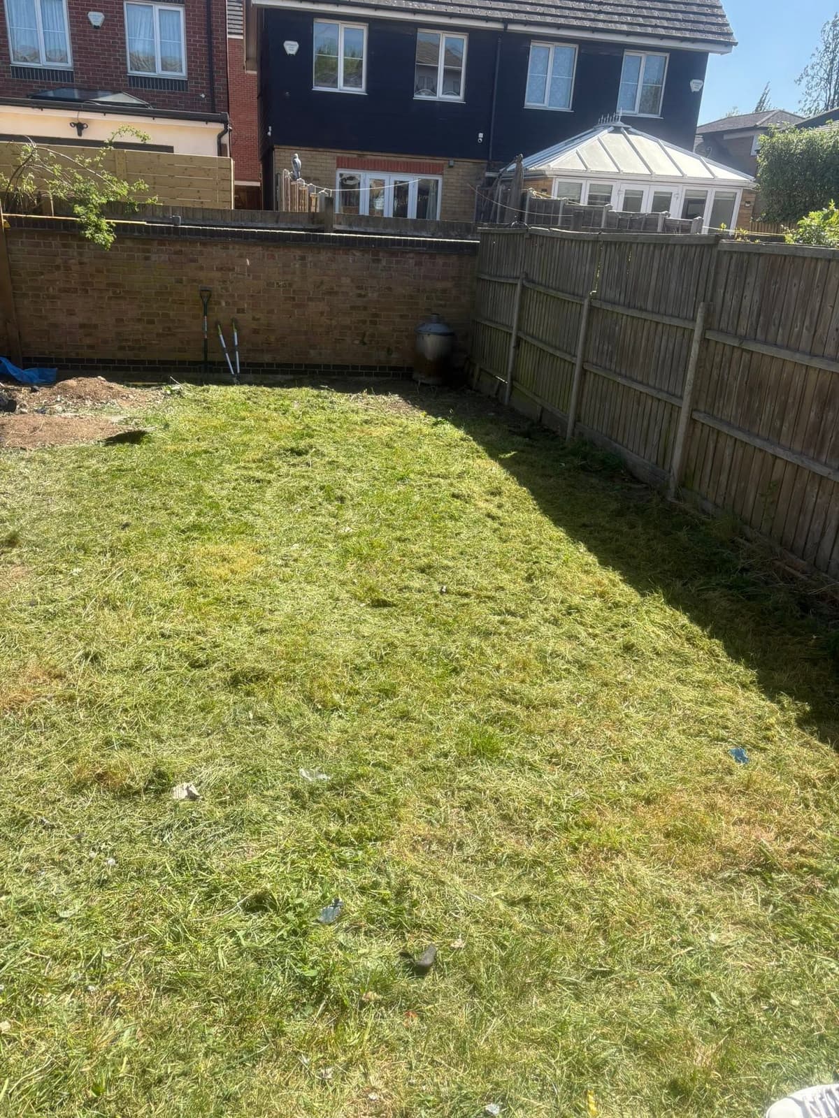 The same back garden after clearance, with the lawn cut and the rubbish removed