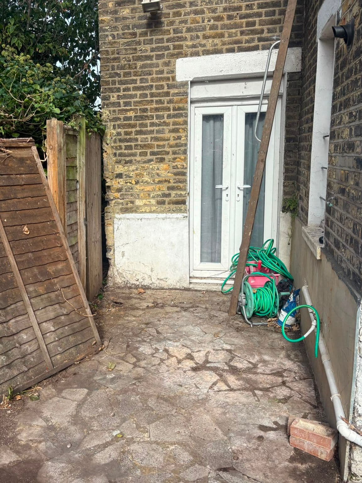 The same side garden after clearance, with the trimmings and rubbish removed and the paving clear