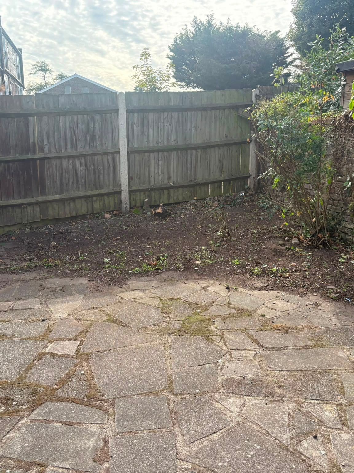 The same back garden after clearance, with the branches removed and the patio and soil bed clear