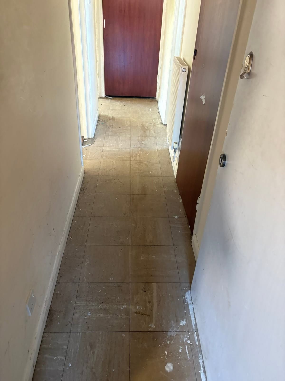 The same hallway emptied after the house clearance, with a clear tiled floor
